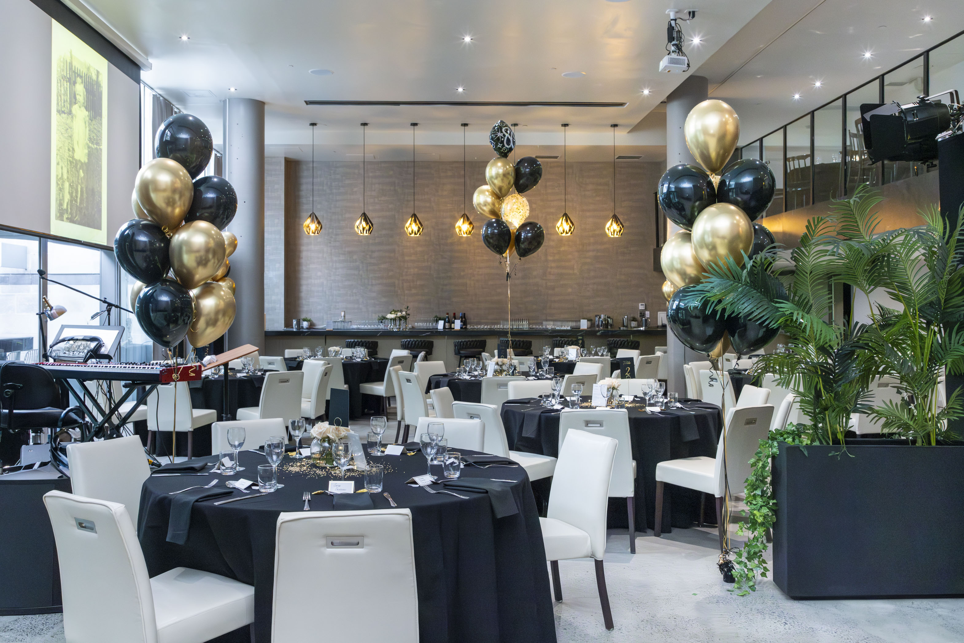 une salle avec des tables et des ballons noirs et dorés